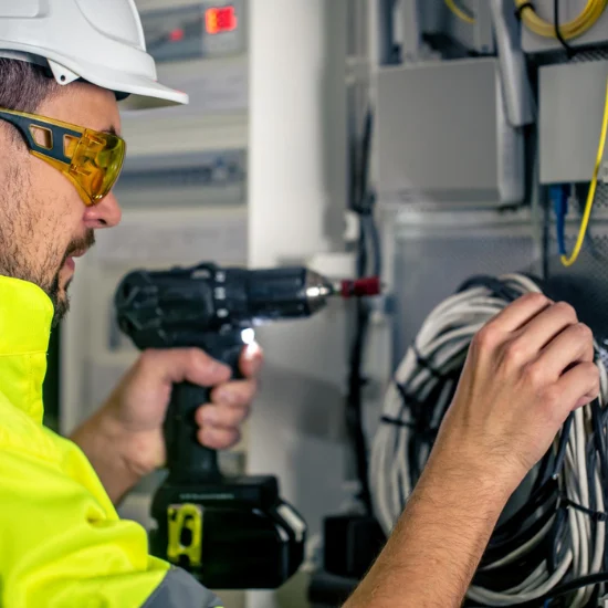 Test and tag worker holding a drill and some cords.