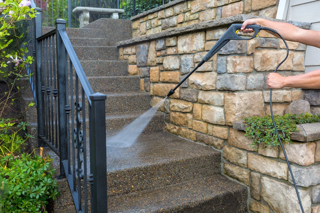 Man pressure washing his house's outdoor stairs.