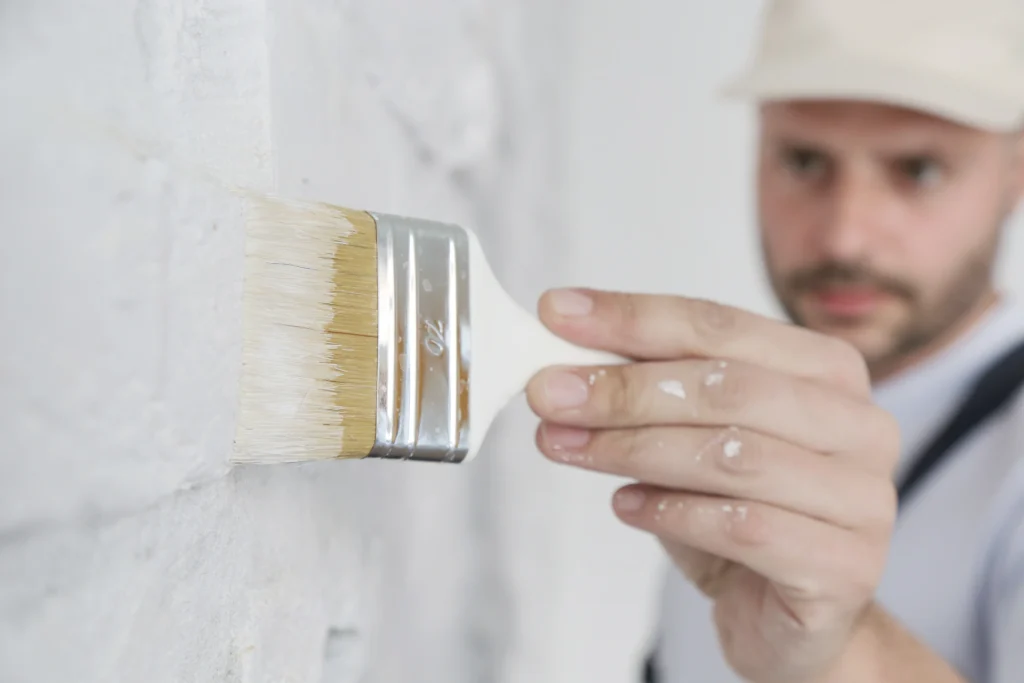 Professional painter painting a house wall white.