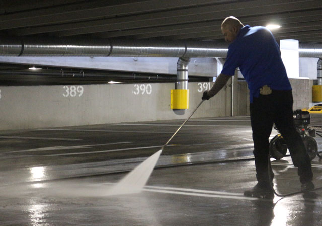 Worker performing high-pressure cleaning in an indoor car park in Melbourne