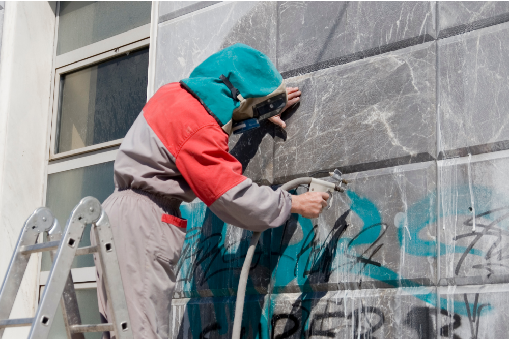 Graffiti removal professional in Melbourne cleaning graffiti from a marble wall using precision tools.