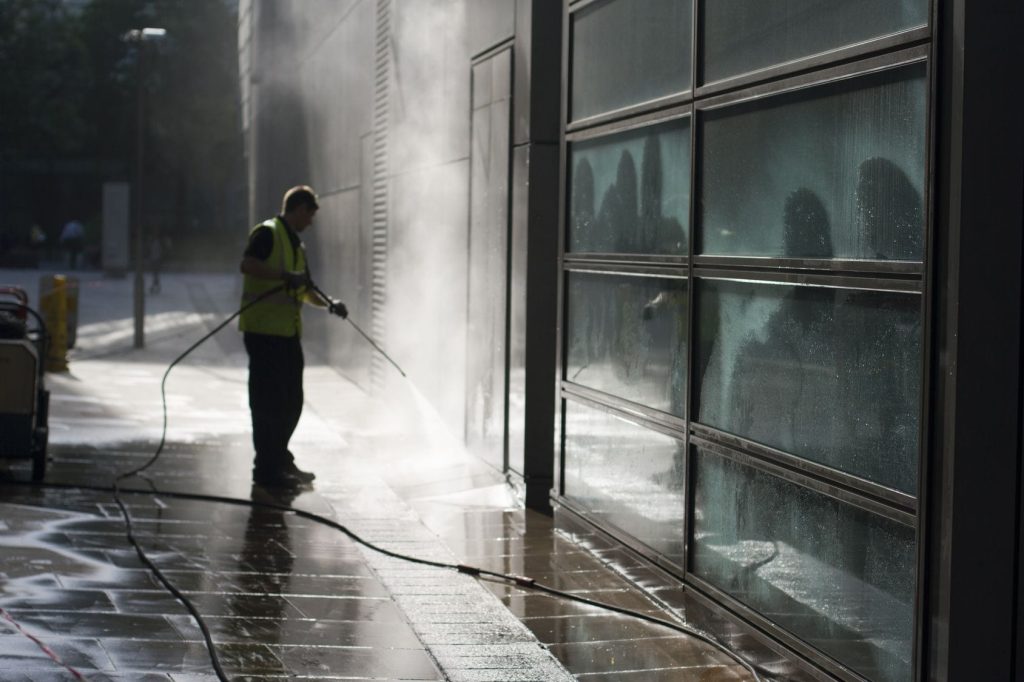 Professional performing high-pressure washing on a building and pavement in Melbourne