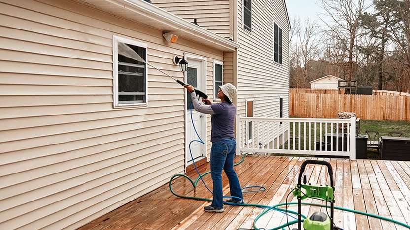 A professional performing soft washing services on the exterior siding of a house in Melbourne, ensuring a clean and refreshed appearance.