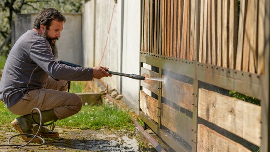 Man pressure washing a wooden fence as part of professional fence cleaning services in Melbourne.