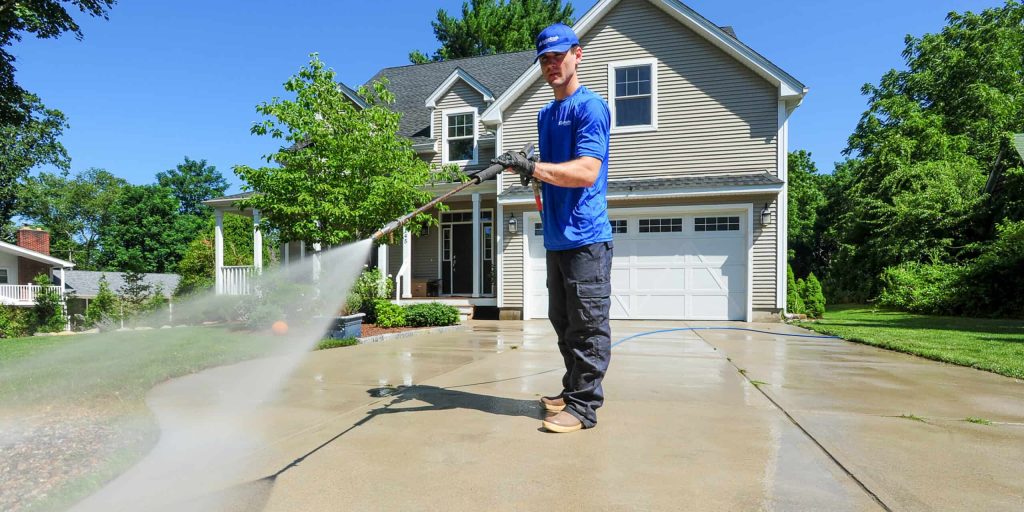 A professional performing soft washing services on a house exterior in Melbourne, effectively removing dirt and grime with a low-pressure water spray.