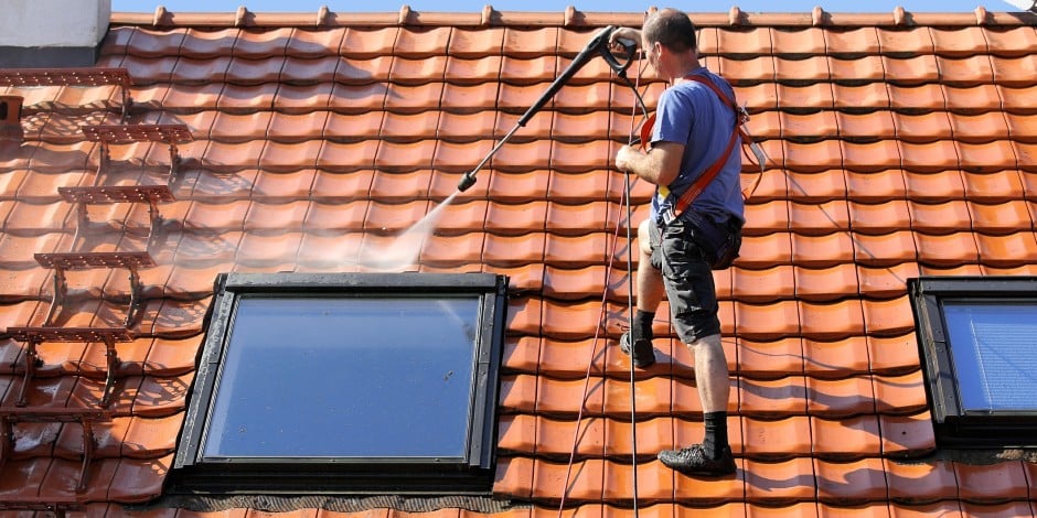 A professional using soft washing services to clean a red tile roof in Melbourne, ensuring safe and thorough results.