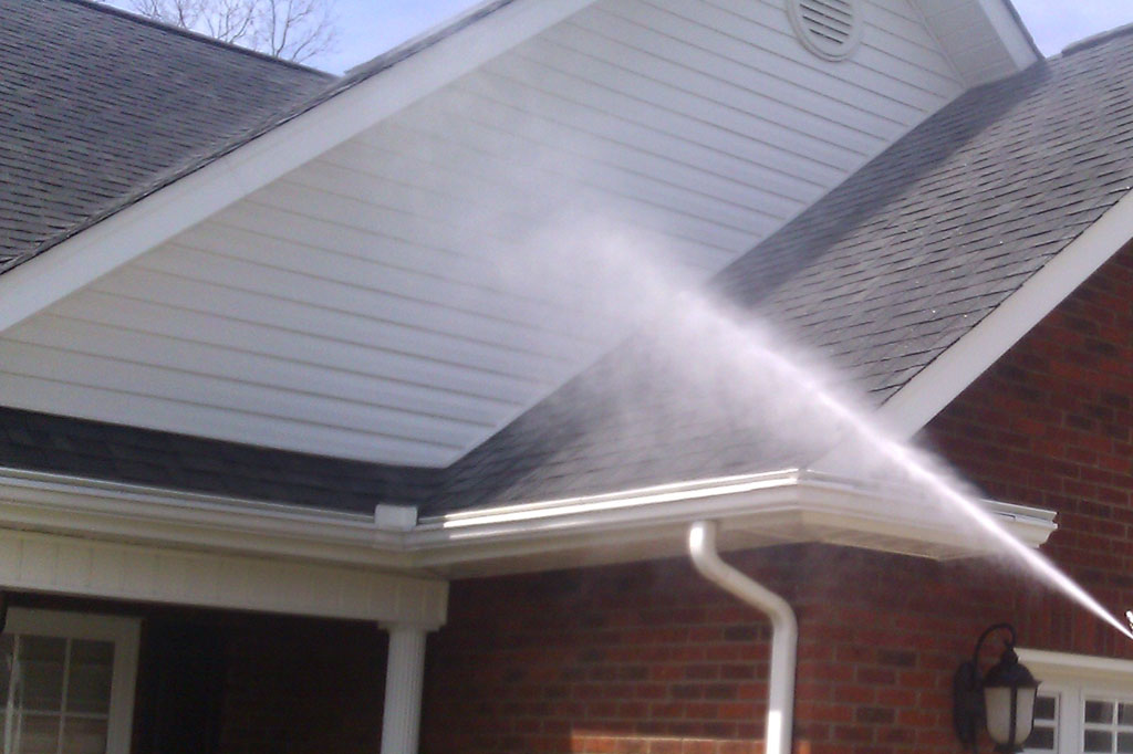 A soft washing service in action on the exterior of a house in Melbourne, effectively cleaning the roof and siding using low-pressure water spray.