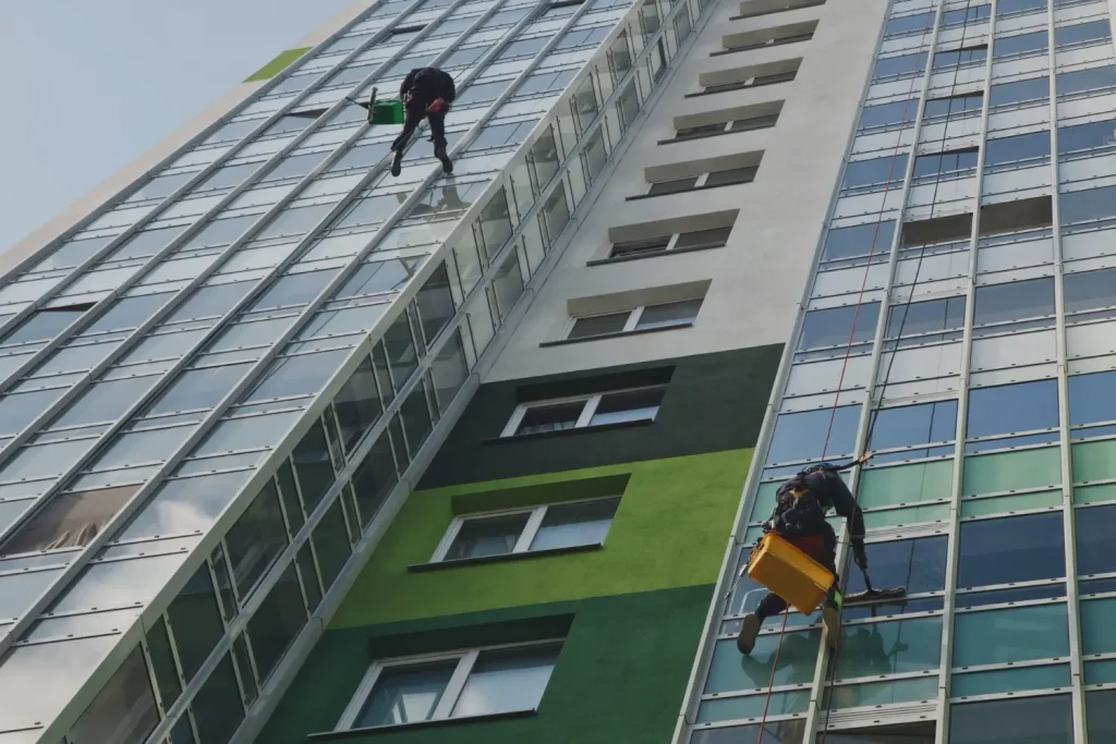 Worker using a high-powered washer to clean a stained driveway Full Building Exterior Cleaned
