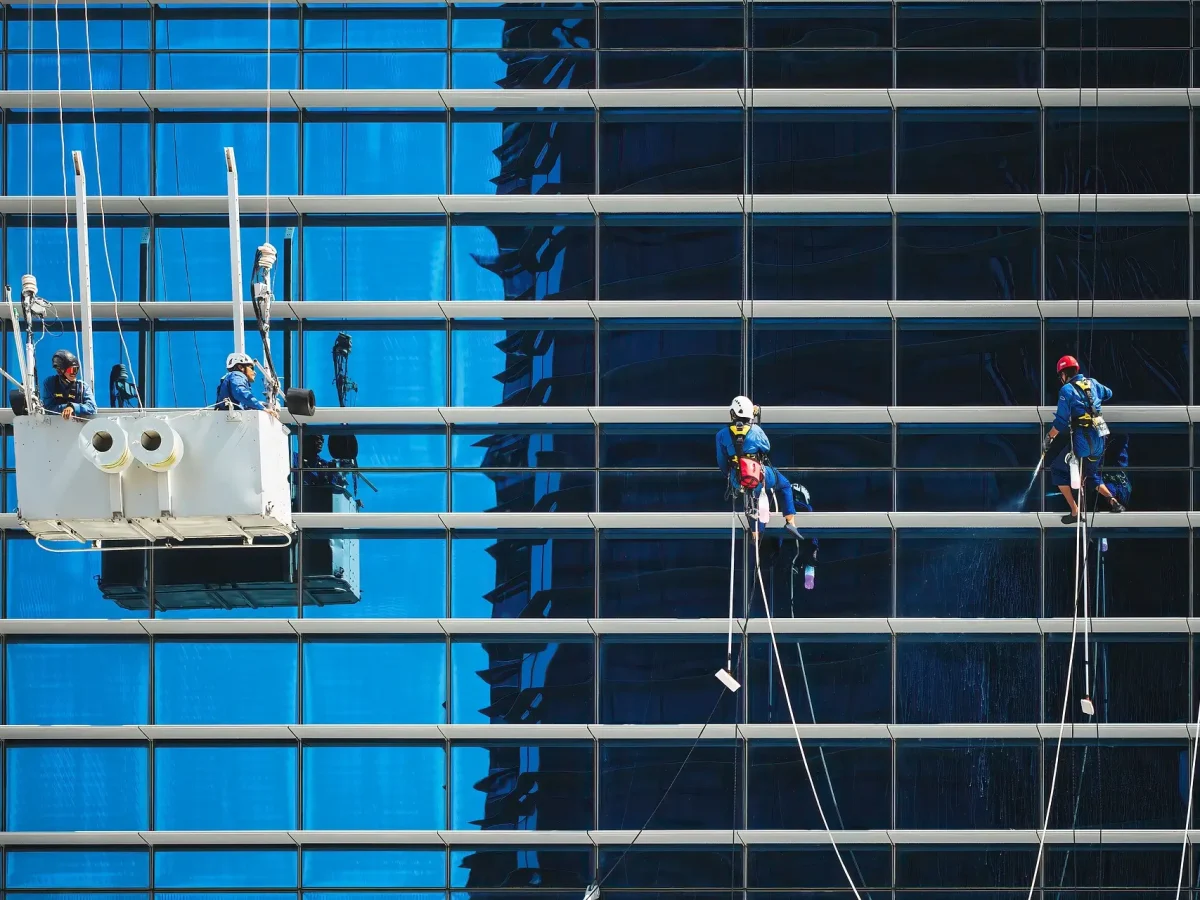 Workers cleaning the side of a building while suspended in the air.